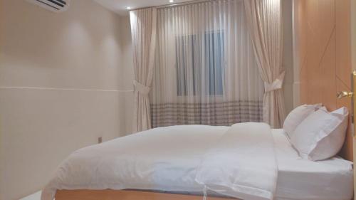 a white bed in a room with a window at شاليه ارض السعاده 1 in Obhor