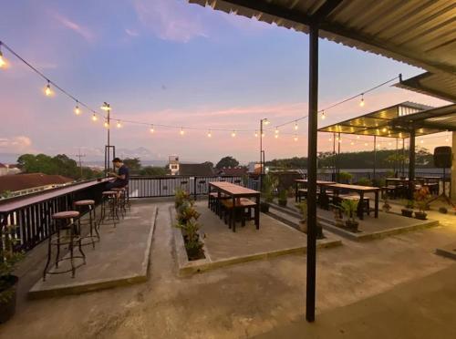 a rooftop patio with tables and chairs and lights at Ador 46 Homestay Syariah & Kost in Mergan
