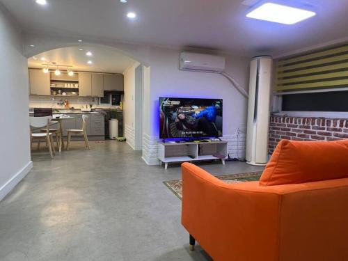 salon z pomarańczową kanapą i telewizorem w obiekcie Hongdae HK Stay w Seulu