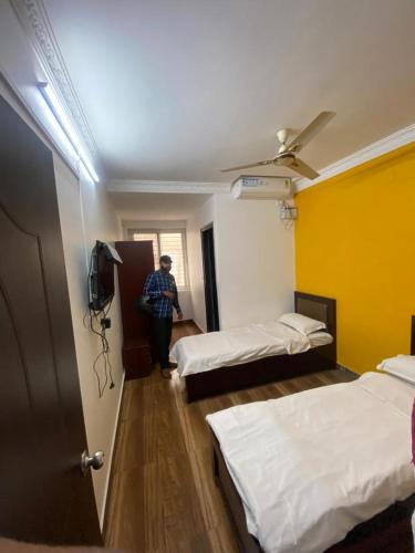 uma pessoa de pé num quarto com duas camas em Royal Colive & Suits em Bangalore