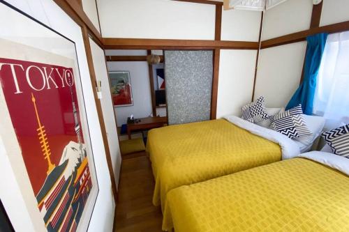 two beds in a room with yellow sheets and a mirror at Good aces to Shibuya/2mins walk sta/Max12ppl/1flor in Tokyo