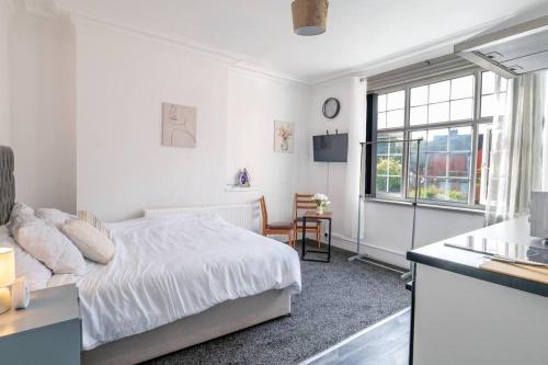 a white bedroom with a bed and a kitchen at Deluxe Studio: Studio Suite 10 in Parkside