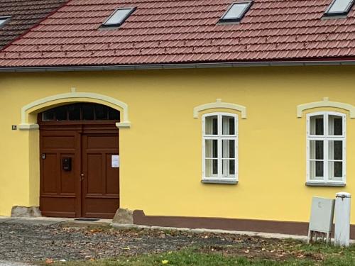a yellow house with a brown door and windows at Zu Hause in Vrbov