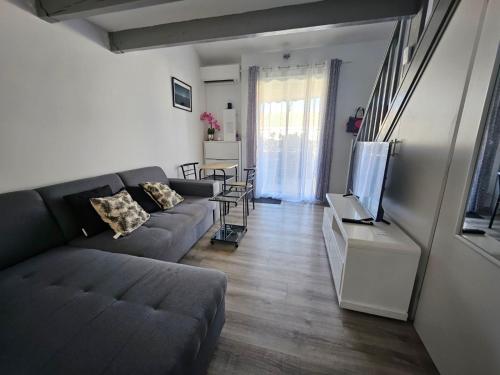 a living room with a couch and a flat screen tv at Résidence naturiste Éden plage in Port Leucate