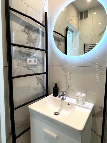 une salle de bain avec un lavabo et un miroir dans l'établissement le studio Molitor, à Boulogne-Billancourt