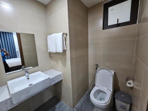 ein Badezimmer mit einem Waschbecken, einem WC und einem Spiegel in der Unterkunft Serviced apartment with pool- Greenpearl Bắc Ninh in Hòa Ðình