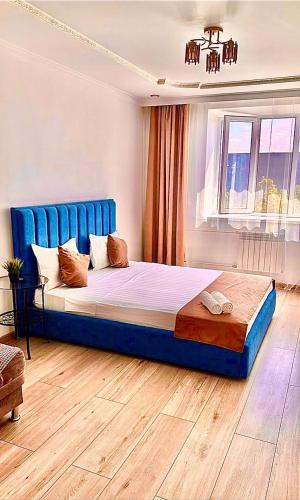 a bedroom with a large bed with a blue headboard at Аблайхана 1/3 in Kokshetau