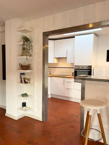 une cuisine avec des placards blancs, une table et un tabouret dans l'établissement Appartement à pied du centre avec place de parking, à Arles
