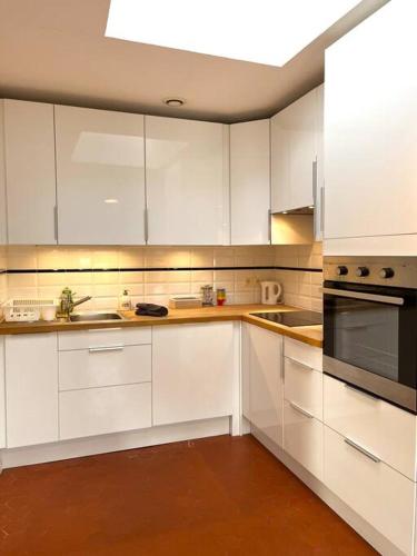 une cuisine avec des armoires blanches et un four à plaques de cuisson dans l'établissement Appartement à pied du centre avec place de parking, à Arles