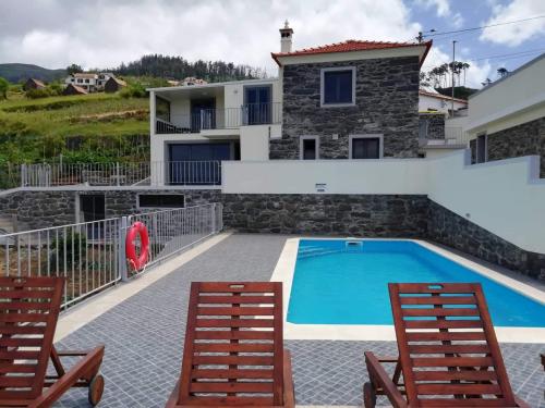 a villa with a swimming pool and two chairs at Quinta Escola in Arco da Calheta
