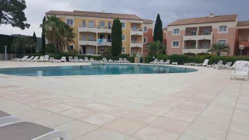 - une piscine avec des chaises blanches et des bâtiments dans l'établissement CHARMANT APPARTEMENT T2 VUE SUR PISCINE, aux Issambres