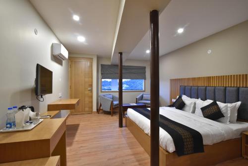 een hotelkamer met een groot bed en een bureau bij Hotel M Bar and Restaurant in McLeod Ganj