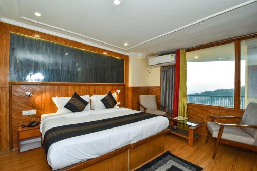 een slaapkamer met een bed, een stoel en een raam bij Hotel M Bar and Restaurant in McLeod Ganj