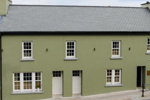 a green house with white windows and a gray roof at WITHIN THE VILLAGE in Galway