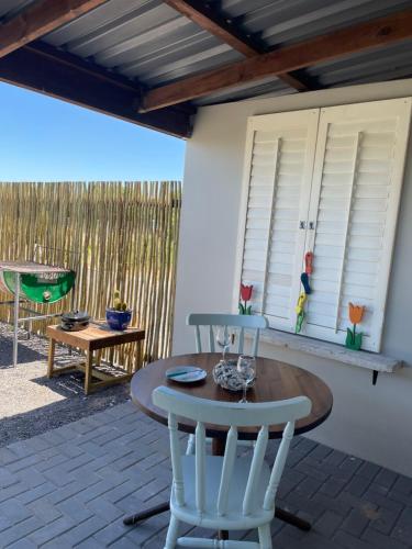 a patio with a table and chairs and a swing at Villiera Guest Farm in Langebaan