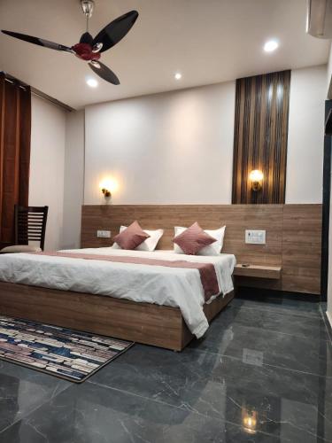 a bedroom with a large bed and a ceiling fan at Namay Inn By T AND M Hotels in Haridwār