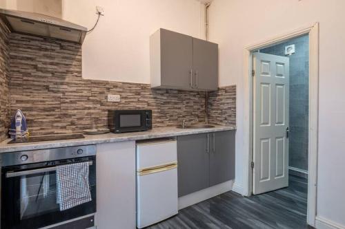 a kitchen with white cabinets and a brick wall at Cosy City: Studio Suite 7 in Parkside