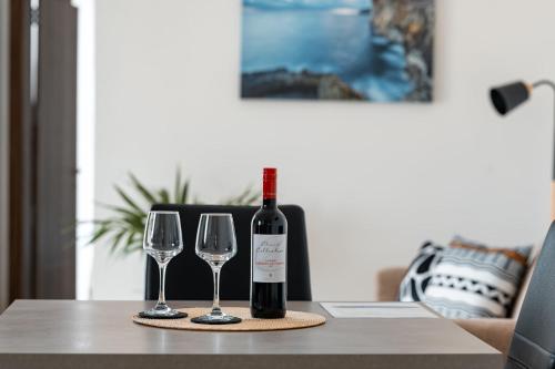 a bottle of wine and two wine glasses on a table at The Willows Penthouses with Jacuzzi in Għajn il-Kbira