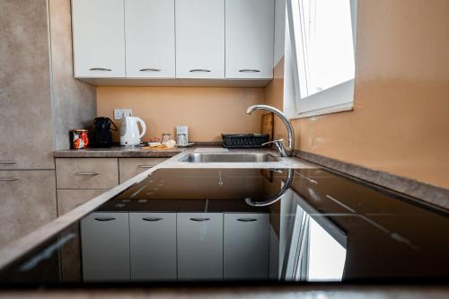 a kitchen with white cabinets and a sink at The Willows Penthouses with Jacuzzi in Għajn il-Kbira