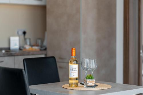 a bottle of wine sitting on a table with a wine glass at The Willows Penthouses with Jacuzzi in Għajn il-Kbira