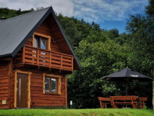 a log cabin with an umbrella and a table at Kryjówka Yetiego Domek w zaciszu Bieszczad z jacuzzi in Hoczew