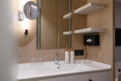 La salle de bains est pourvue d'un lavabo blanc et d'un miroir. dans l'établissement Hotel Stiemerheide, à Genk