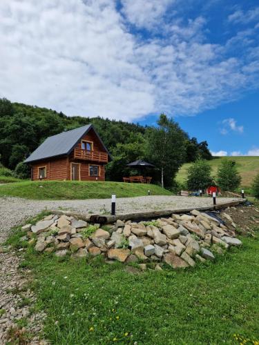 a log cabin and a stone wall in front of a house at Kryjówka Yetiego Domek w zaciszu Bieszczad z jacuzzi in Hoczew