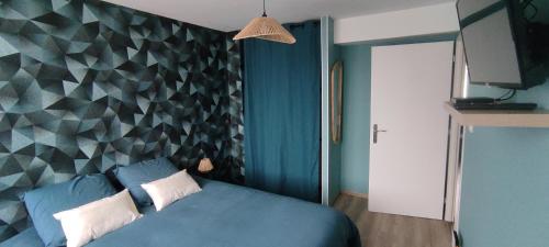 ein Schlafzimmer mit einem blauen Bett und einer geometrischen Wand in der Unterkunft Au Terrier in Bettancourt-la-Ferrée