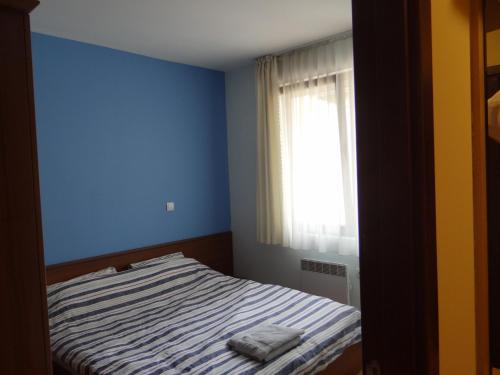 - une chambre avec un lit aux murs bleus et une fenêtre dans l'établissement Bansko Ski Apartment, à Bansko