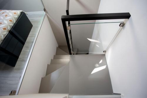 une cage d'escalier avec une rampe en verre et un lit dans l'établissement Domus 25, à Catane