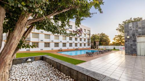 an apartment building with a pool and a tree at African Sky Ermelo Inn in Ermelo