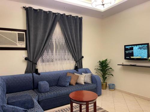 a blue couch in a living room with a window at فخامة المصيف للشقق المخدومة 2 in Taif