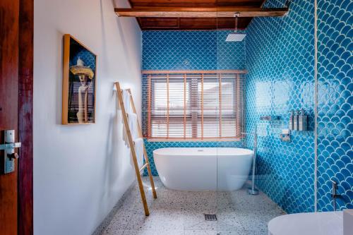 a bathroom with a tub and blue tiles at Koh Apikjun Resort in Kaoh Sdach