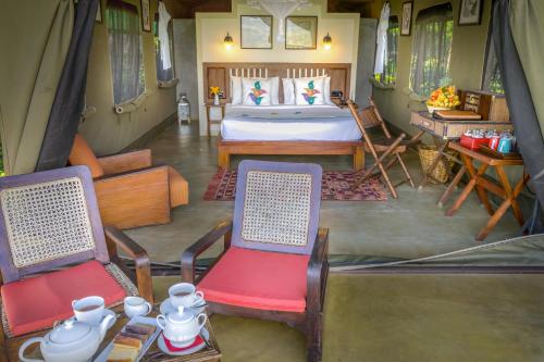a bedroom with a bed and two chairs and a table at Madulkelle Tea and Eco Lodge in Kandy