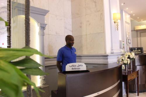a man standing at a desk in a lobby at Maysan Al Mashaer Hotel in Makkah
