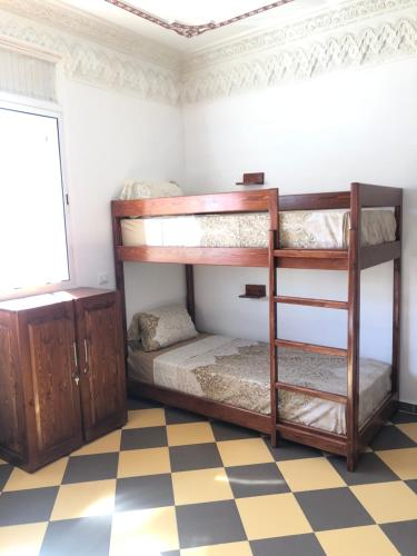 two bunk beds in a room with a checkered floor at TOODA House in Imsouane