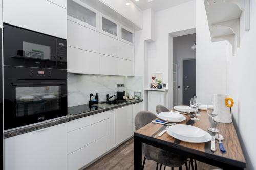una cucina con tavolo, sedie e piano cottura di Malila Premium Apartments Cracow Centre Starowiślna 43 a Cracovia