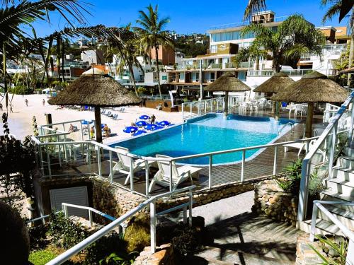 einen Pool mit Stühlen und Sonnenschirmen in einem Resort in der Unterkunft Bombinhas Tourist Apart in Bombinhas
