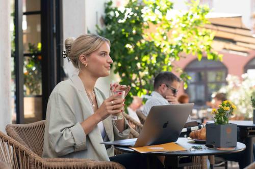 a woman sitting at a table with a laptop at Abbate Boutique Hotel in Ulm
