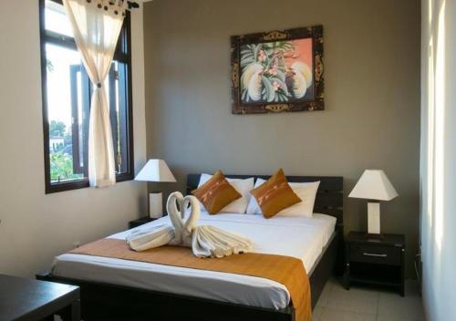 a bedroom with two beds and a picture on the wall at Meilds Property Kuta in Kuta