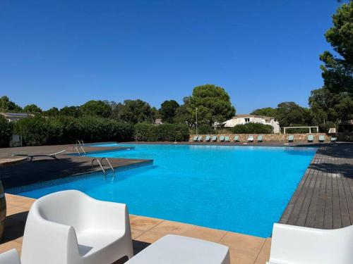 une grande piscine avec des chaises blanches et de l'eau bleue dans l'établissement Havre de paix Fiori di Cala Rossa, à Lecci
