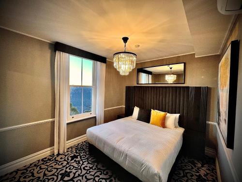 a bedroom with a bed and a window and a chandelier at Hydro Majestic Blue Mountains in Medlow Bath