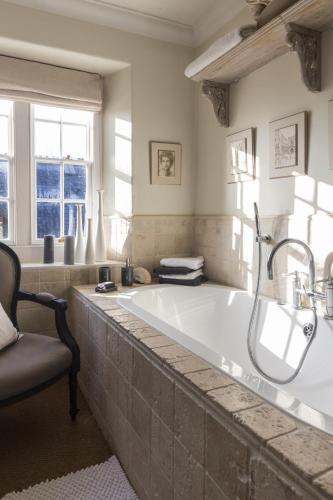 a large bathroom with a large tub with a chair at Roundhill Farmhouse in Bath