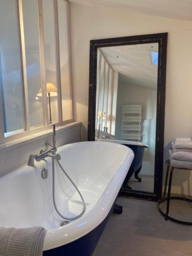 a bathroom with a tub and a large mirror at Hôtel Le Sénéchal in Ars-en-Ré