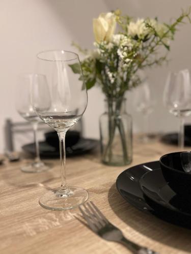 a table with two wine glasses and a vase of flowers at Balnéo, Lumineux, Confort in Colmar