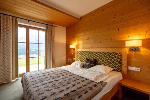 sypialnia z dużym łóżkiem i drewnianą ścianą w obiekcie Chalet Bergmueller w Schladming