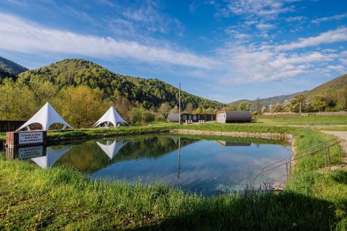 a small pond with tents and mountains in the background at Рибничанка in Skhidnitsa