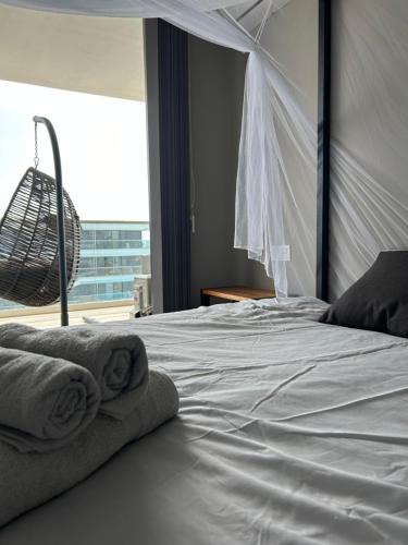 una camera da letto con un letto bianco e asciugamani di Far Out Apartments - Kololi Sands a Sere Kunda