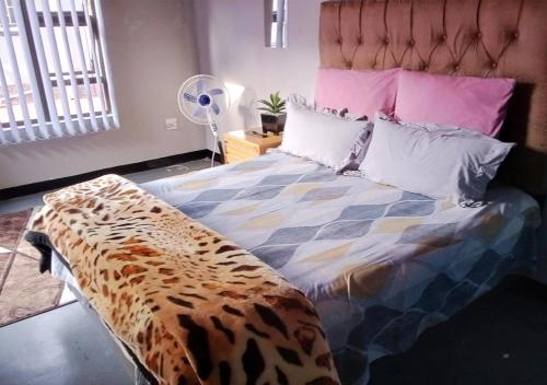 Schlafzimmer mit einem Leopardenbett und einem Ventilator in der Unterkunft NSK GUEST HOUSE in Alberton