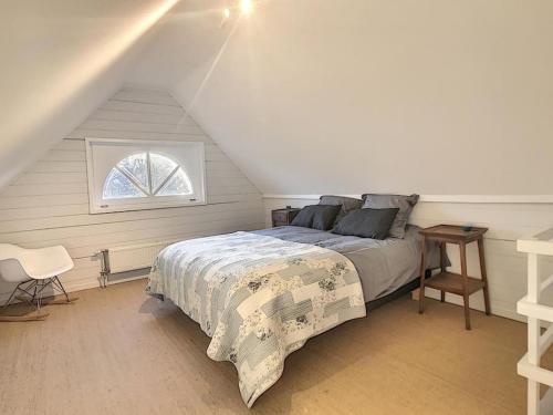 um quarto com uma cama num sótão com uma janela em Cottage en bordure bruxelloise em Wezembeek-Oppem